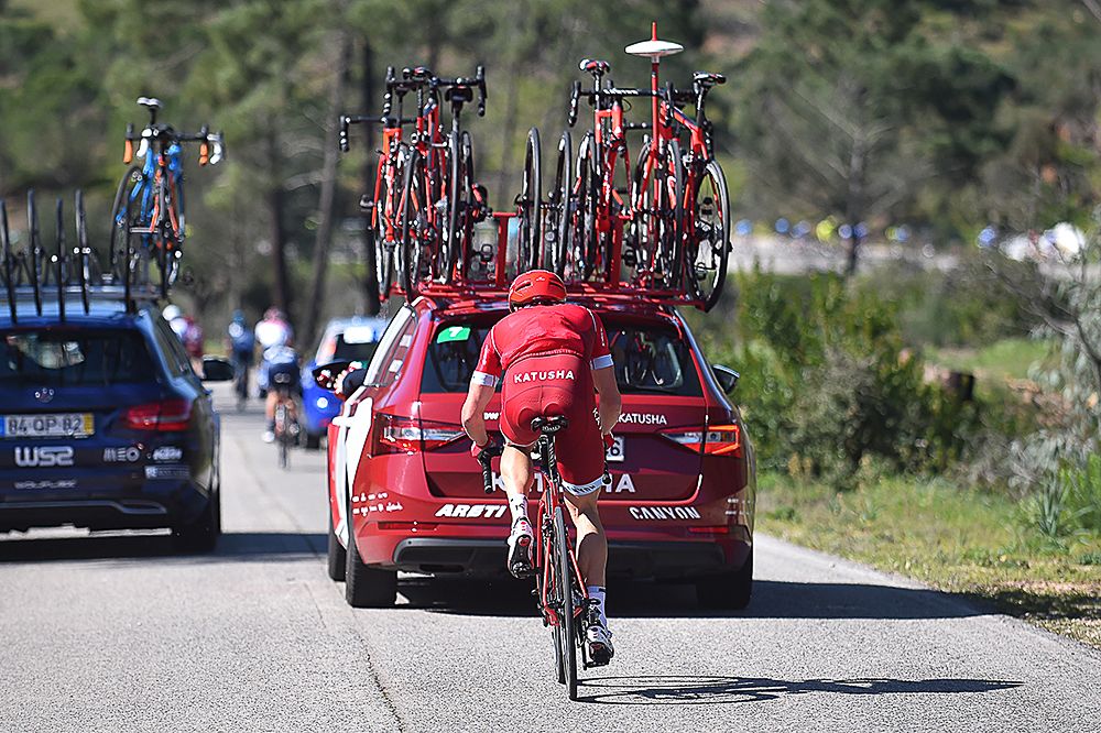 A Katusha rider makes his way back to the peloton after taking a hand up from the team car