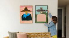 Katie Kime haning Western-inspired wall art from her new collection onto a blank living room wall