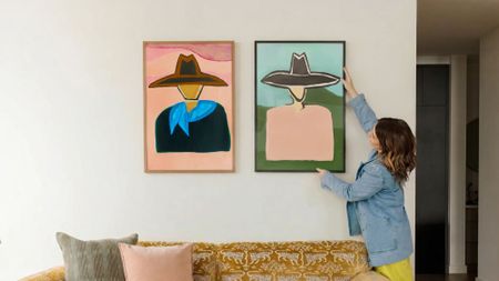 Katie Kime haning Western-inspired wall art from her new collection onto a blank living room wall
