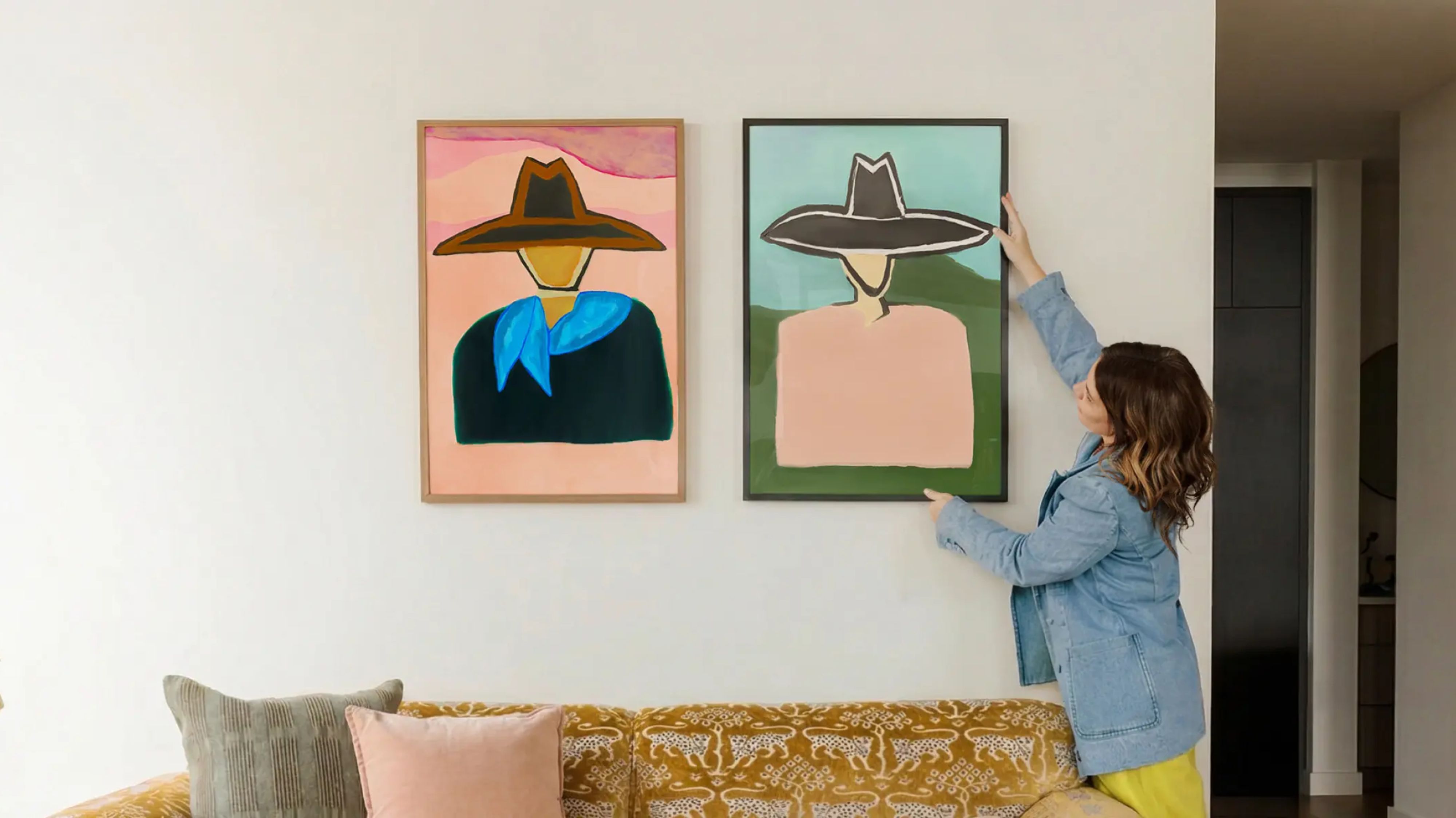 Katie Kime haning Western-inspired wall art from her new collection onto a blank living room wall