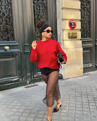 Woman wearing a black sheer maxi skirt and red sweater.