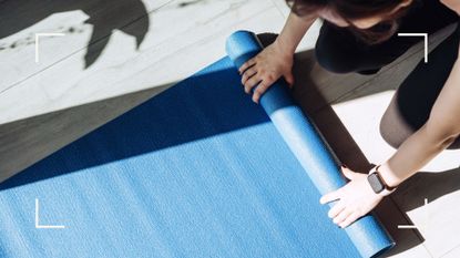 Birds-eye view of woman folding up Pilates mat at home in the sunshine after doing home workout and finding out does wall Pilates really work
