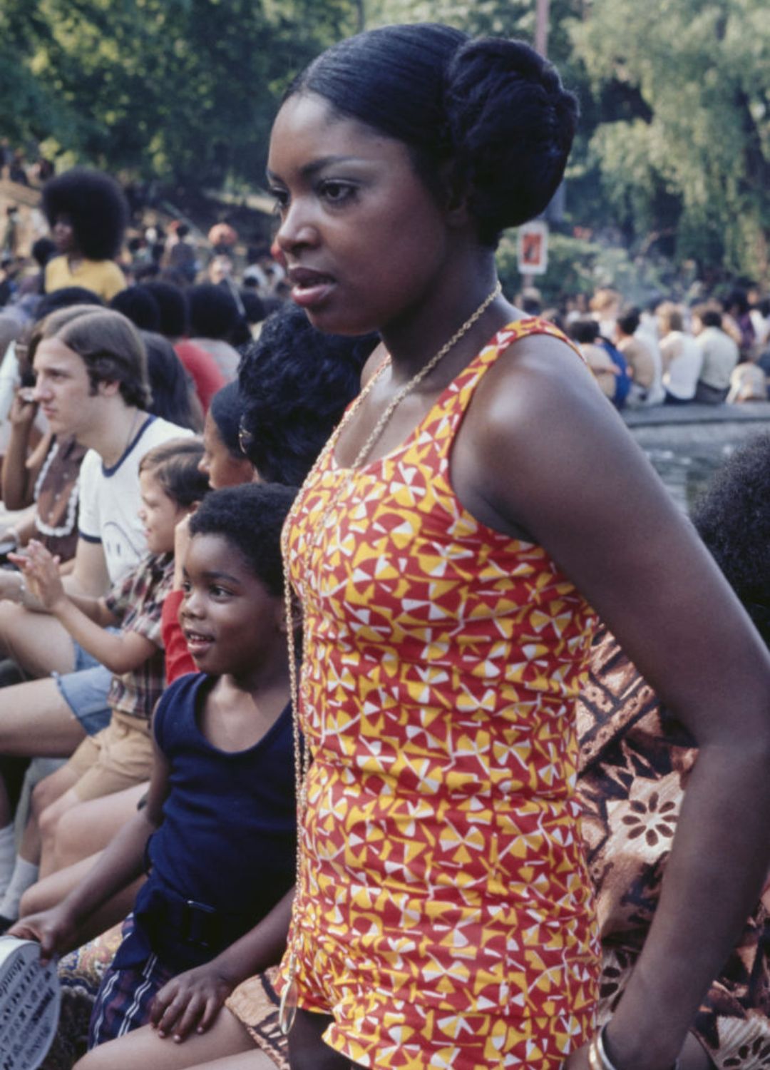 A young woman, wearing a yellow, red and white playsuit, possibly beside the fountain and pool in Washington Square Park, in the Manhattan borough of New York City, New York, circa 1970.