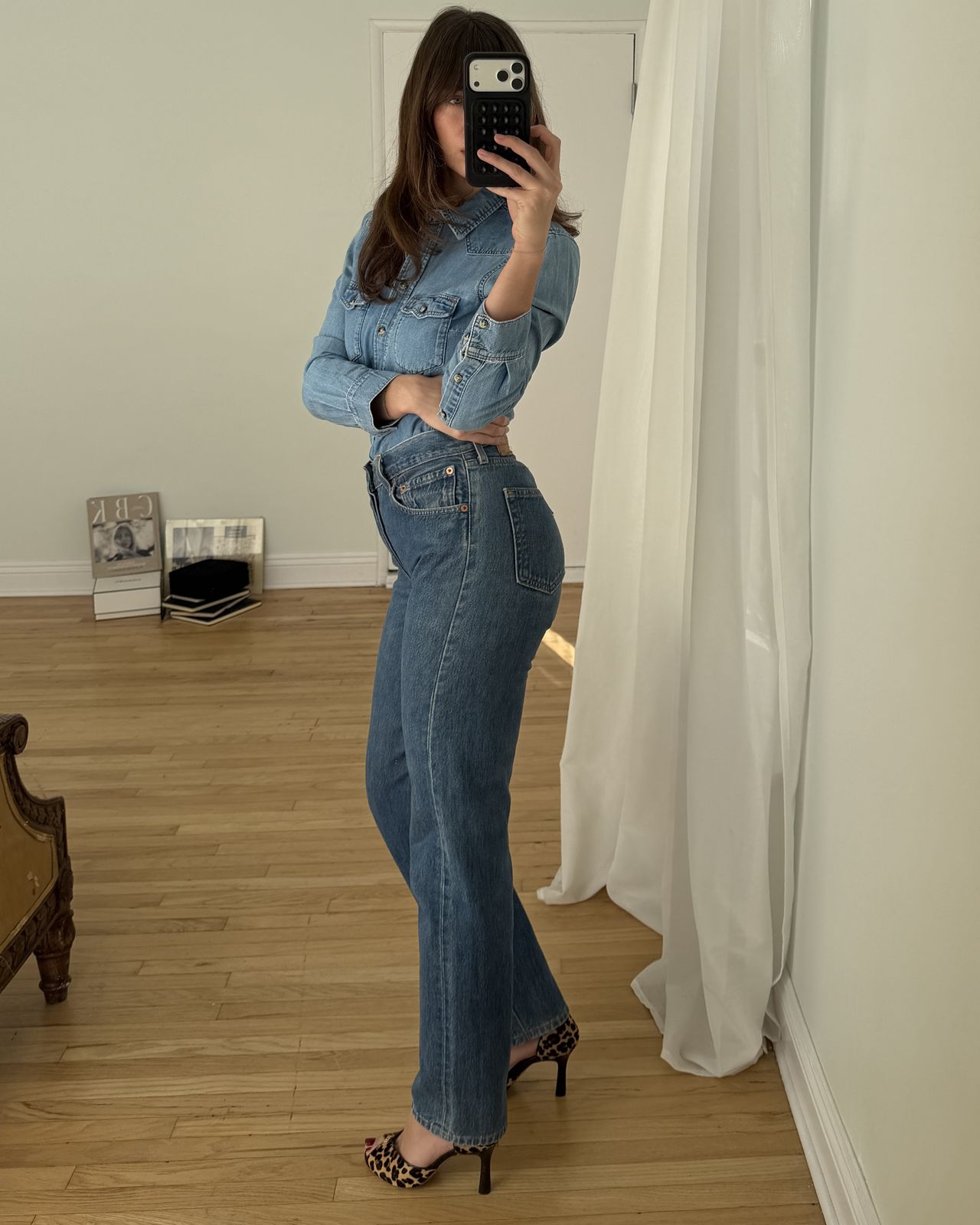 Kathryn Zahorak posing in mirror wearing denim shirt and jeans and leopard print heels
