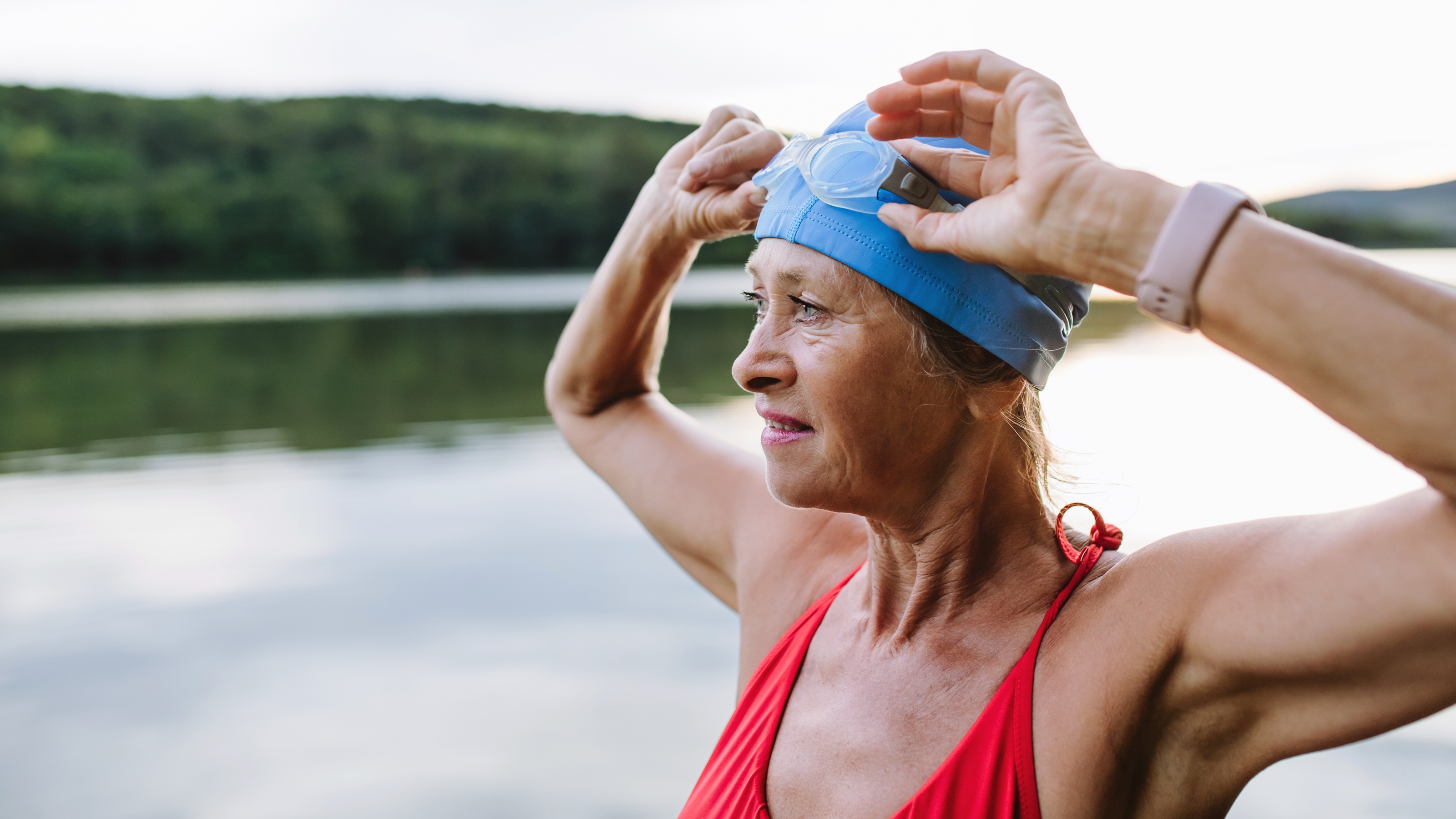 An older woman who has been swimming moves her goggles up.