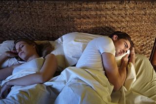 A couple in bed with the man struggling with a sleep disorder.