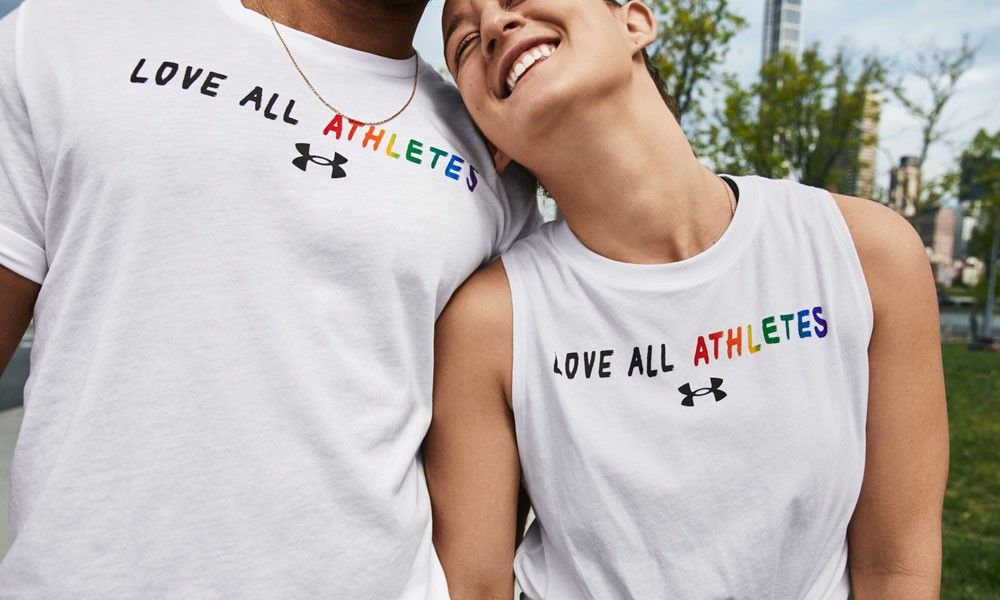 Models wearing a t-shirt with the slogan &#039;love all athletes&#039;, part of the Under Armour Pride Collection