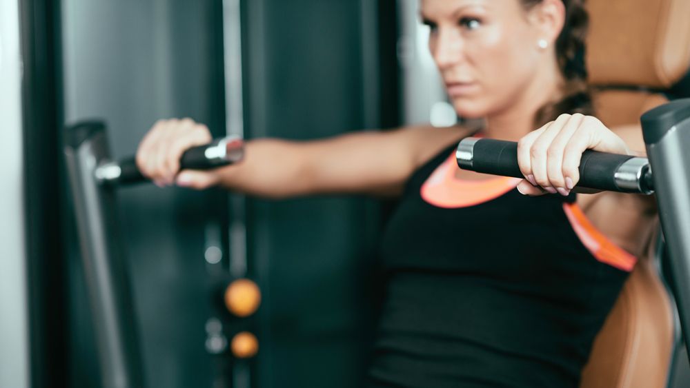 Woman uses chest press machine in gym