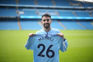 Manchester City's new signing Riyad Mahrez holds a shirt at the Etihad Stadium on July 12, 2018 in Manchester, England.