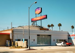 Doug Atiken's studio photographed from the front. White, one story building, with sings placed on the roof. One of them says 'I don't know'.