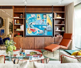 mid-century living room with large wooden open shelving unit, leather chair and blue artwork