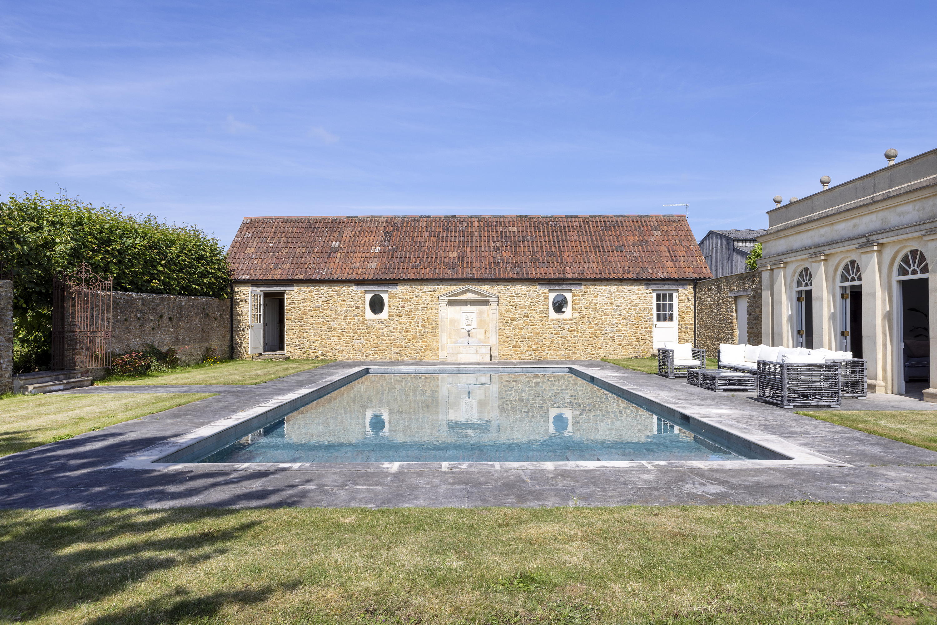 Mount Farm's swimming pool with pool house and outdoor seating beside it