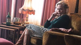 Gillian Anderson sits in an armchair looking dishevelled 