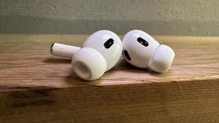 Ett par vita AirPods Pro ligger vid kanten på ett träbord.