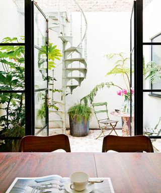 basement with large floor to ceiling glass windows in courtyard with spiral staircase