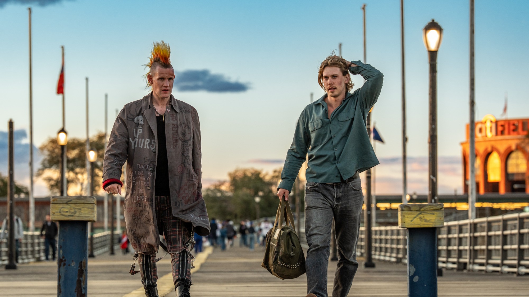 Matt Smith with a Mohawk and Austin Butler walking on a boardwalk in Caught Stealing