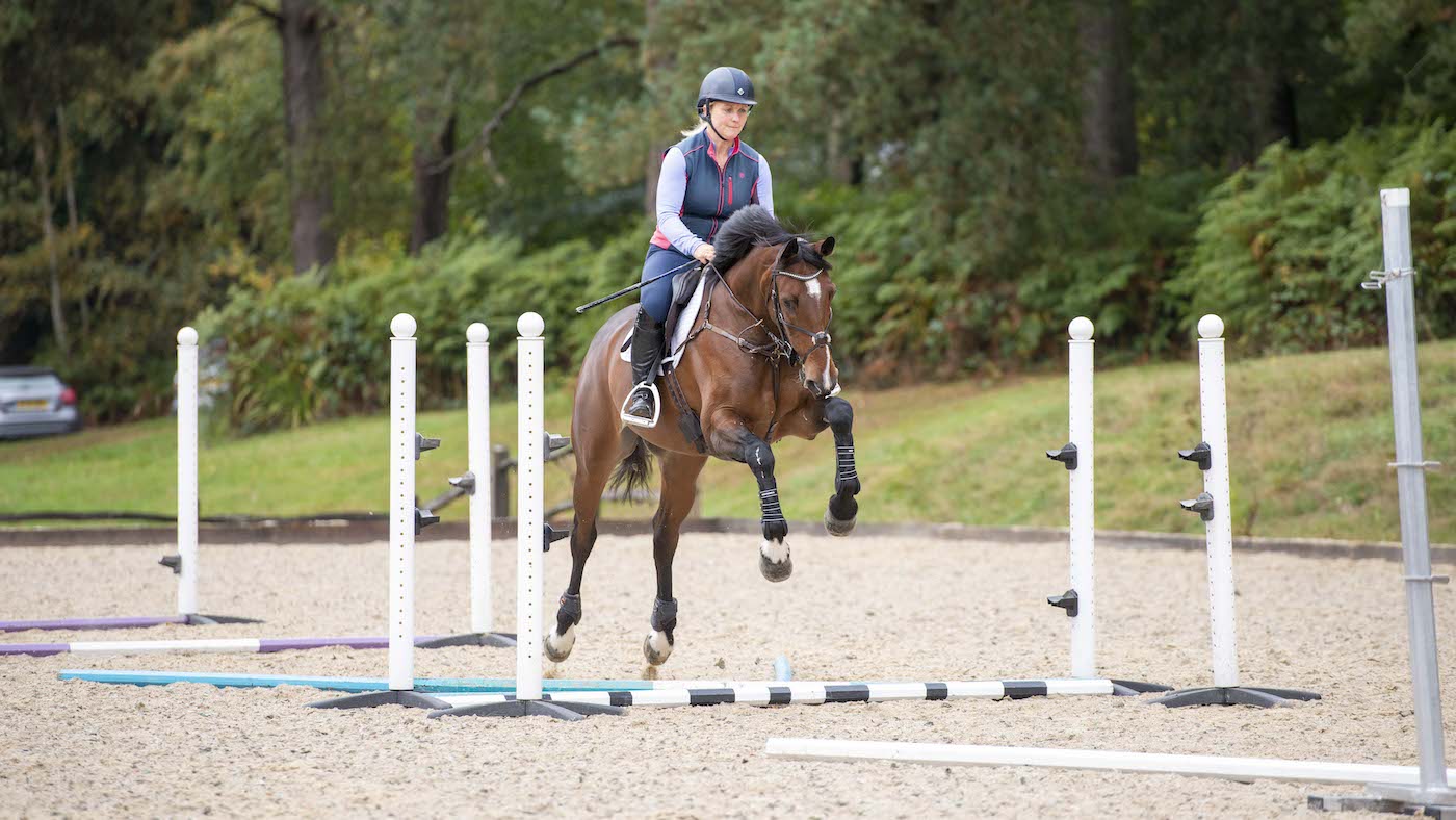 Gemma Stevens preparing for gridwork exercise by cantering over poles