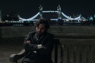 Joe Goldberg sat on a bench in front of Tower Bridge in You season 4