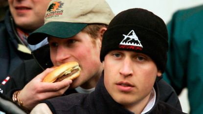 Princes Harry eats a burger while Prince William watches on during the IRB Rugby Aid Match between The Northern Hemisphere and The Southern Hemisphere at Twickenham Stadium on March 5, 2005 in Twickenham, England