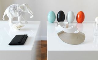 Wooden floor, white wall, two white display platforms, white elephant, black leather wallet, four colourful egg shapes and bespoke design items displayed