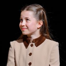 Princess Charlotte smiling in a tan coat