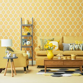 living room with mustard yellow wallpaper sofa set with cushions and coffee table