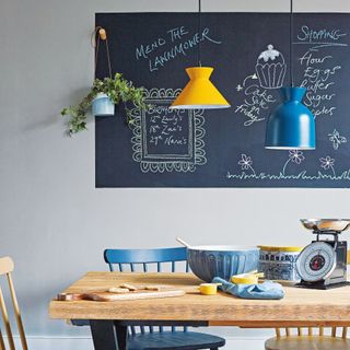 Wall with blackboard wall panel in front of table and pendant light