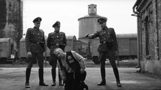 Nazis standing over a Jewish prisoner in Schindler's List