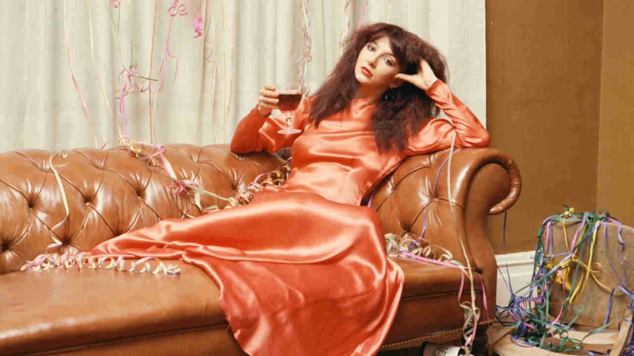 Kate Bush posing for a photograph on a large sofa in 1979