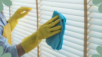 person wiping blinds with a cloth while shut to demonstrate an expert tip for how to clean blinds
