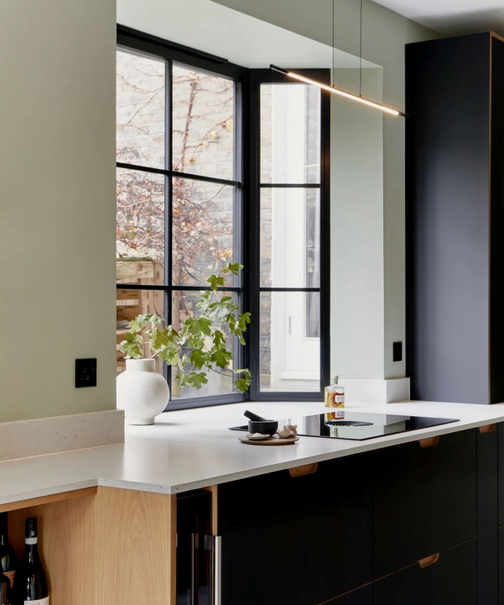 a kitchen counter with an electric stovetop, a bay window and no window treatments