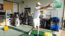 A golfer swinging a bucket of balls