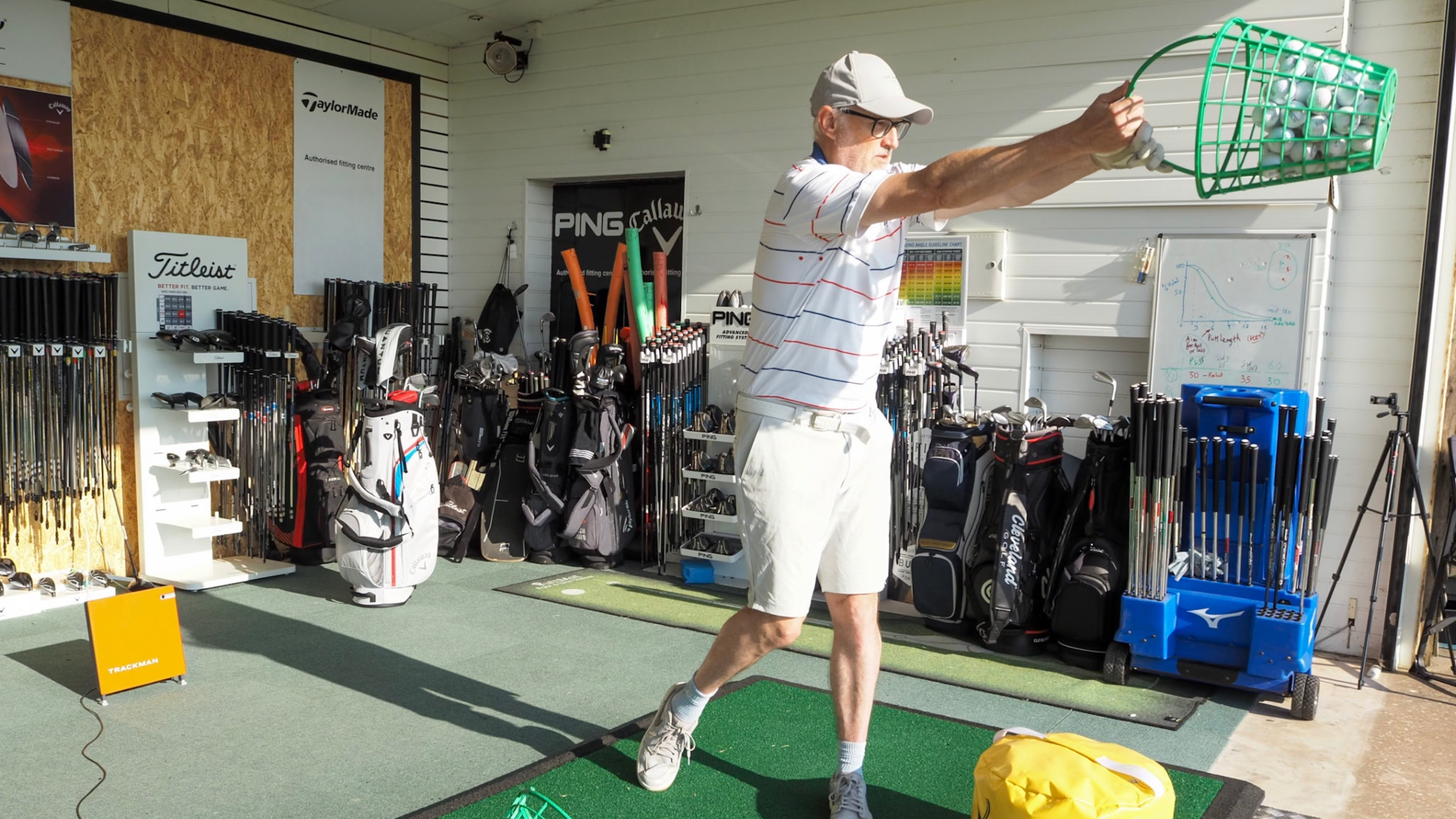 A golfer swinging a bucket of balls