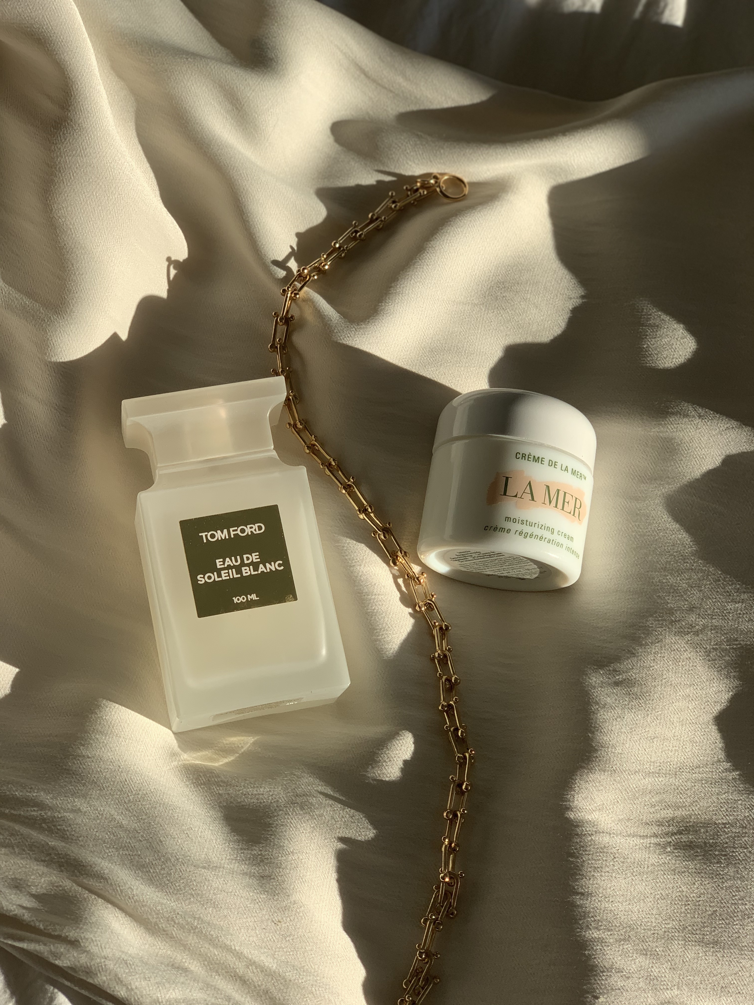 A bottle of Tom Ford Eau de Soileil Blanc on a satin background