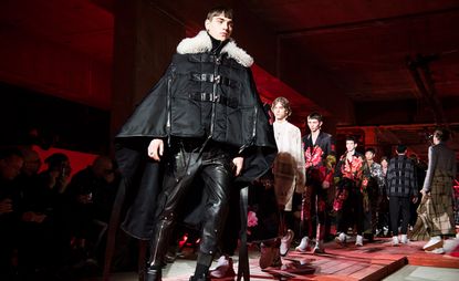 A group of male models on the cat walk modelling Alexander McQueen clothing.