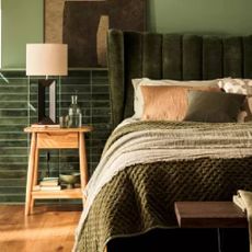 A dark green bedroom with a dark green headboard and a wooden side table from Furniture Village.