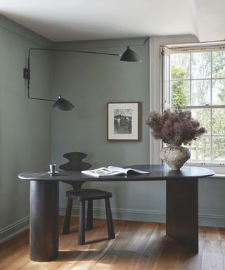 home office corner with curved modern black desk and statement black chair and wall light