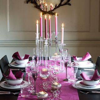 dining table with candles and bowls on plates with napkins