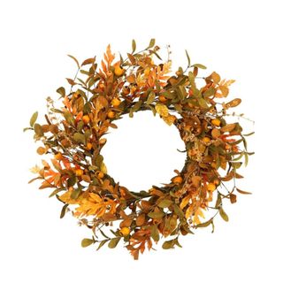 A fall wreath with orange and brown fall leaves and berries around it