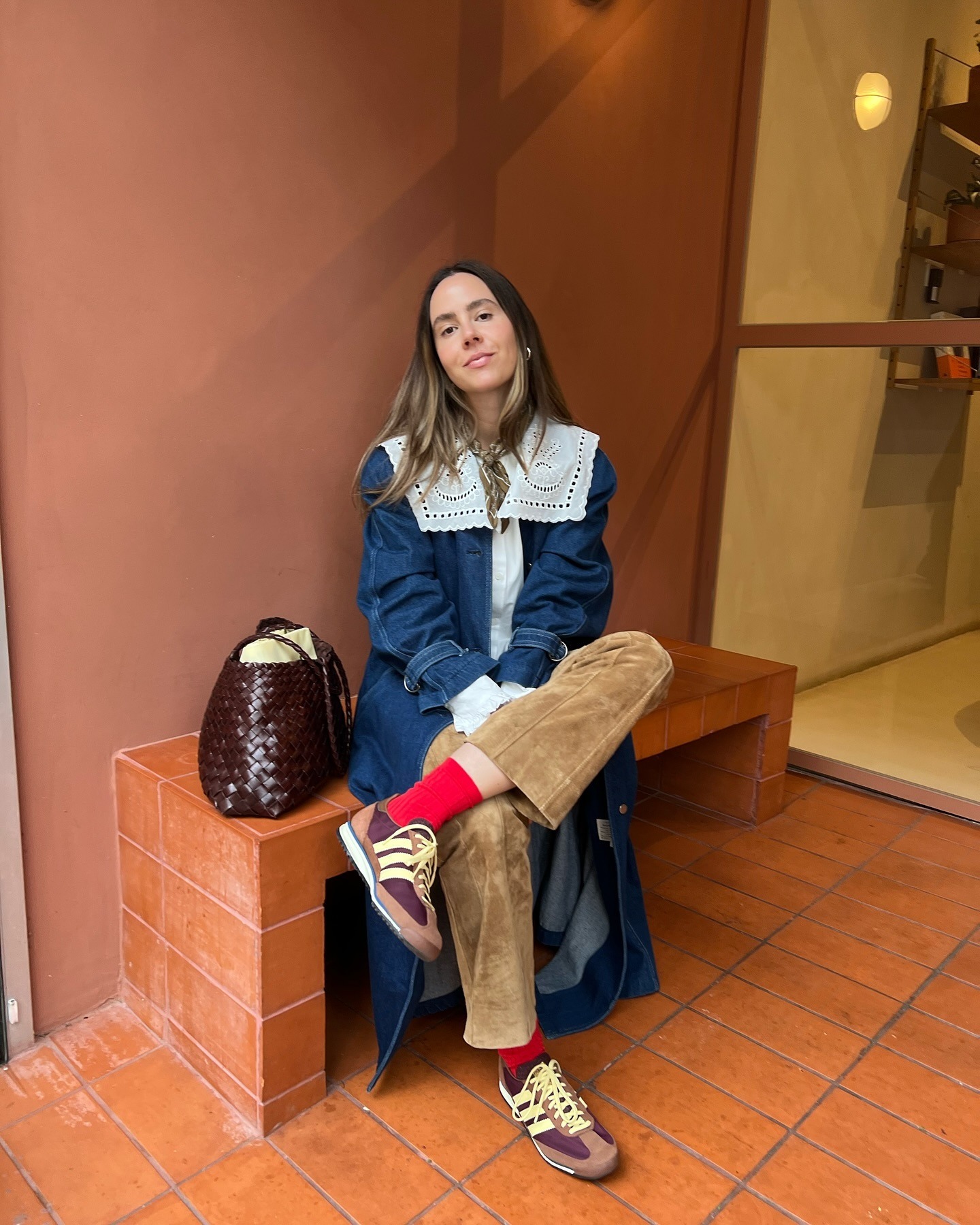 @kristencueto wearing a navy-blue coat, white eyelet collared blouse, Adidas sneakers, and brown suede pants.