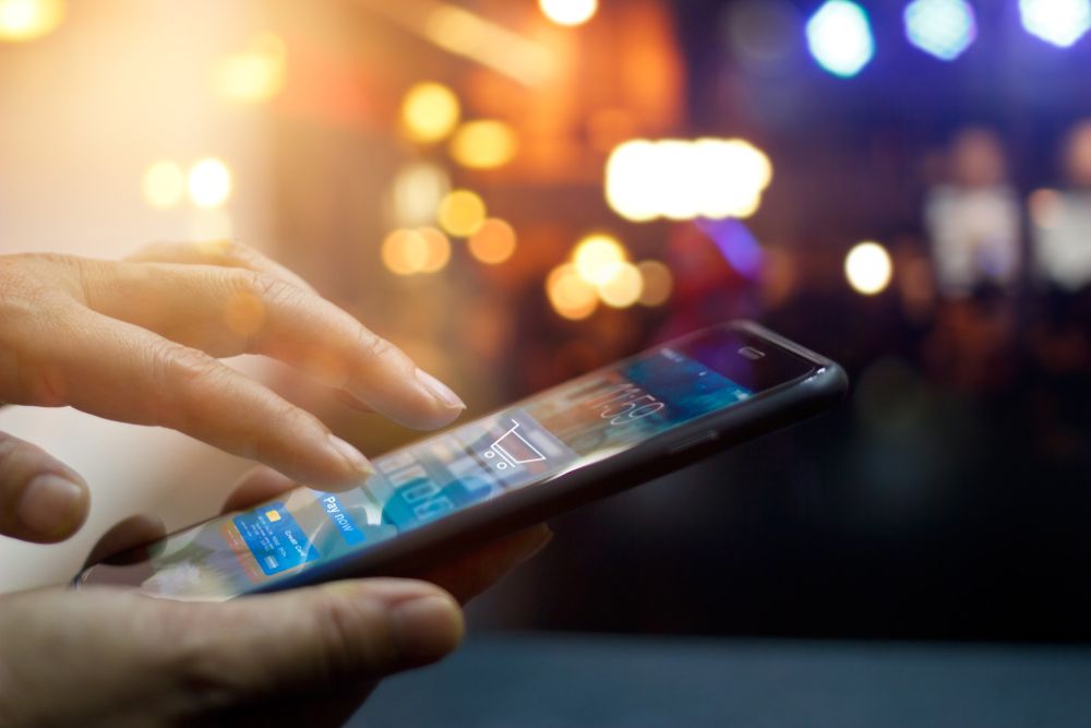 Man using mobile payments in front of a night background