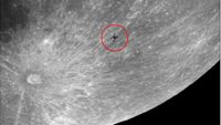 The silhouette of a space station is shown on the lunar surface surrounded by a red circle. A large crater is visible to its lower right, with bright lines emanating outwards.