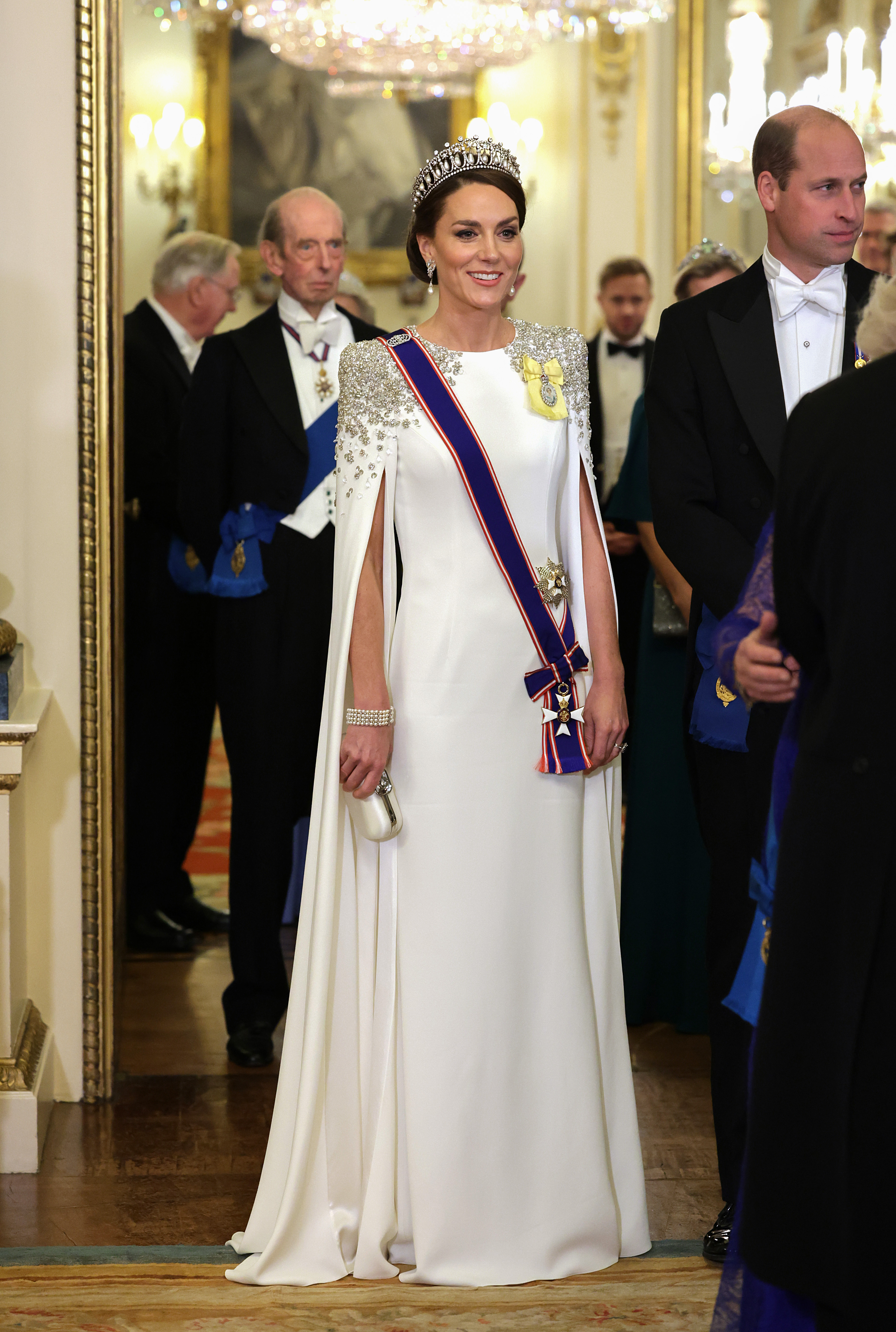 Kate Middleton wearing a tiara and white caped gown