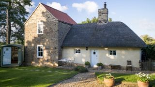 thatched roof on an old cottage and tiled roof on the extension, with a pretty outdoor garden