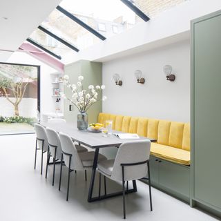 A modern dining area with grey dining chairs and canary yellow banquette seating area
