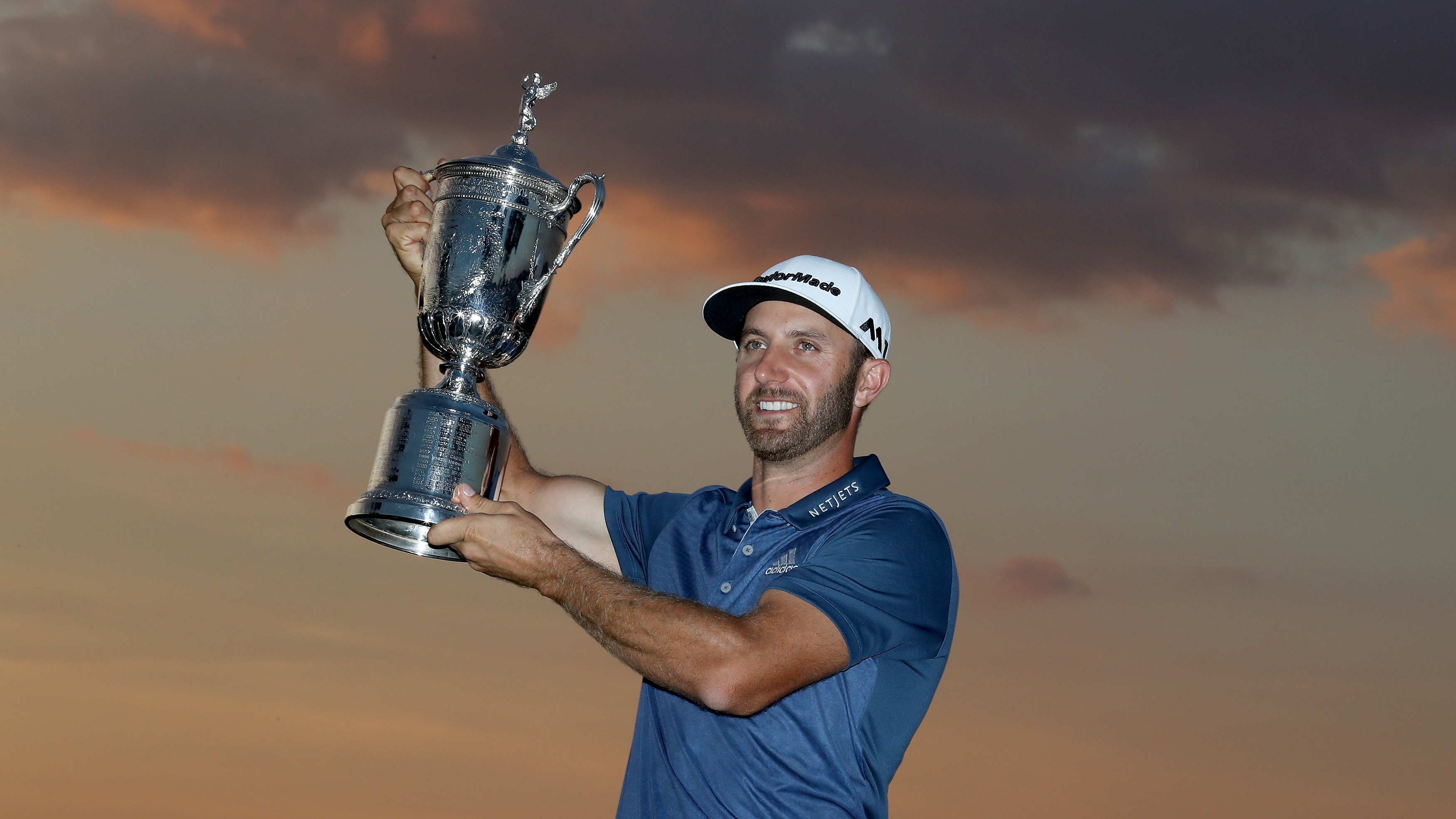 Dustin Johnson smiling while lifting the 2016 US Open
