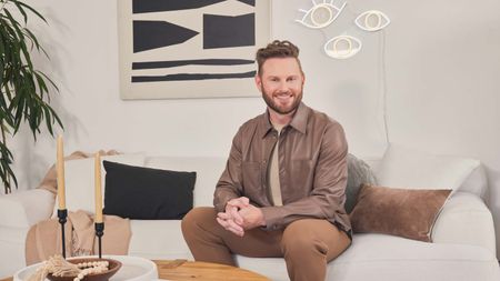 bobby berk on a sofa with his neon lighting