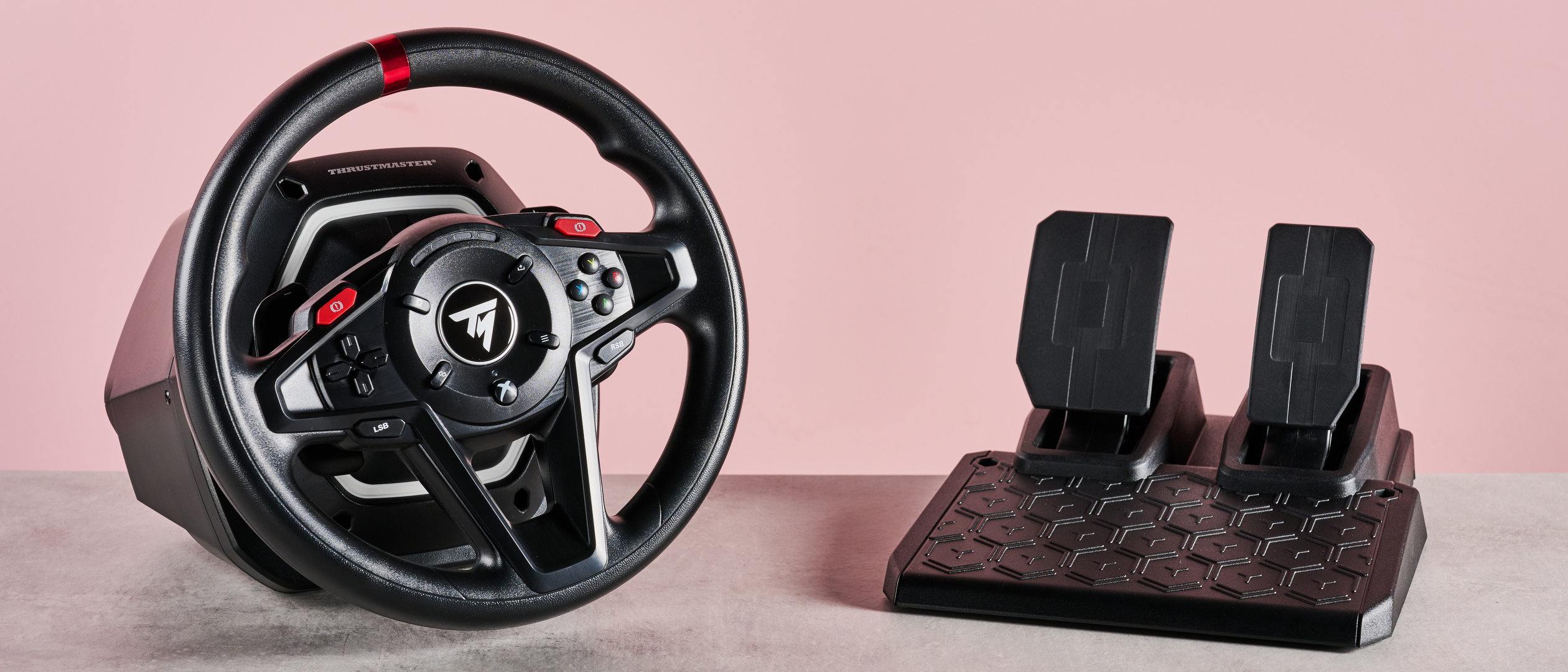 Thrustmaster T128 on desk with pink background