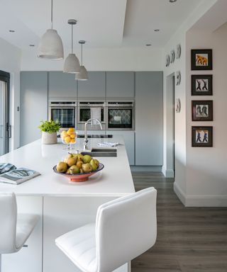 Best kitchen flooring illustrated by wood-look laminate in a white kitchen with breakfast bar.