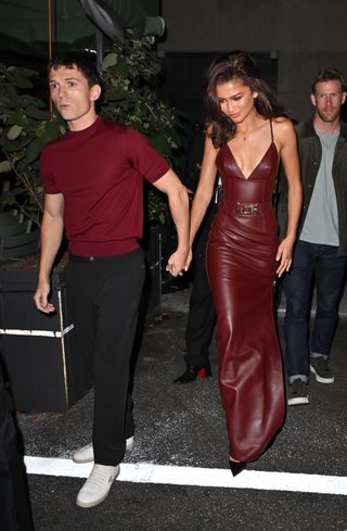 Zendaya wearing a burgundy dress with Tom Holland